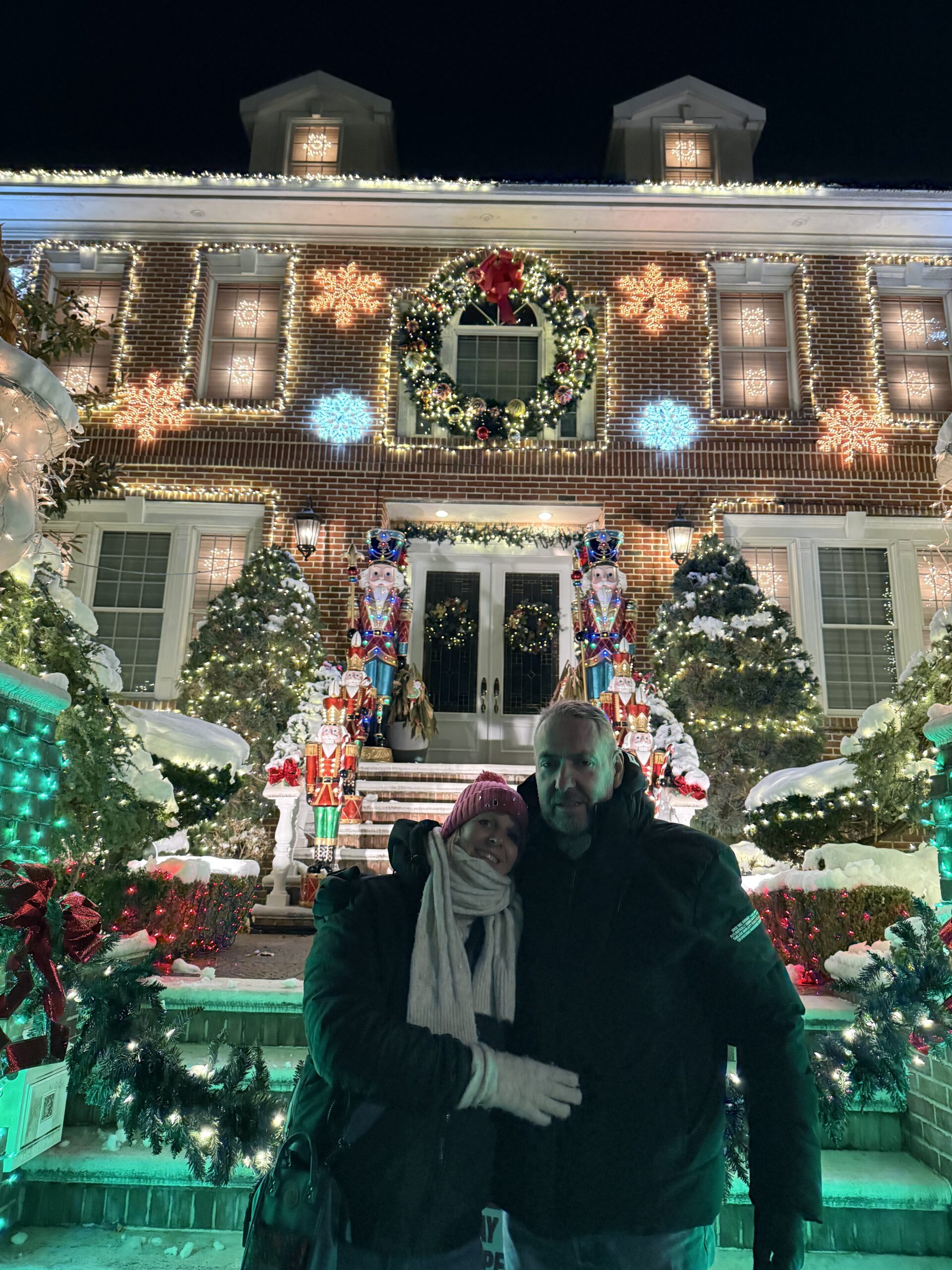 Brooklyn, New York — a man and woman standing in front of a house decorated for christmas