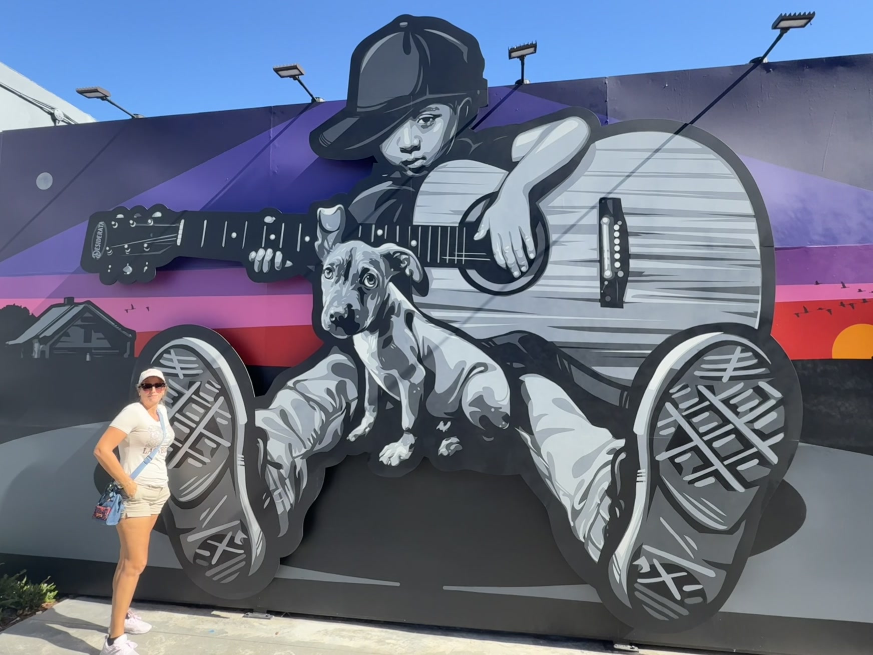 Miami — une femme debout devant une fresque murale représentant un chien et une guitare