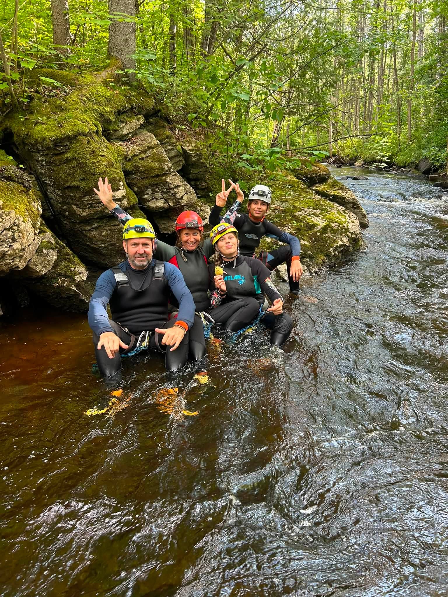 trois personnes en combinaison dans un ruisseau