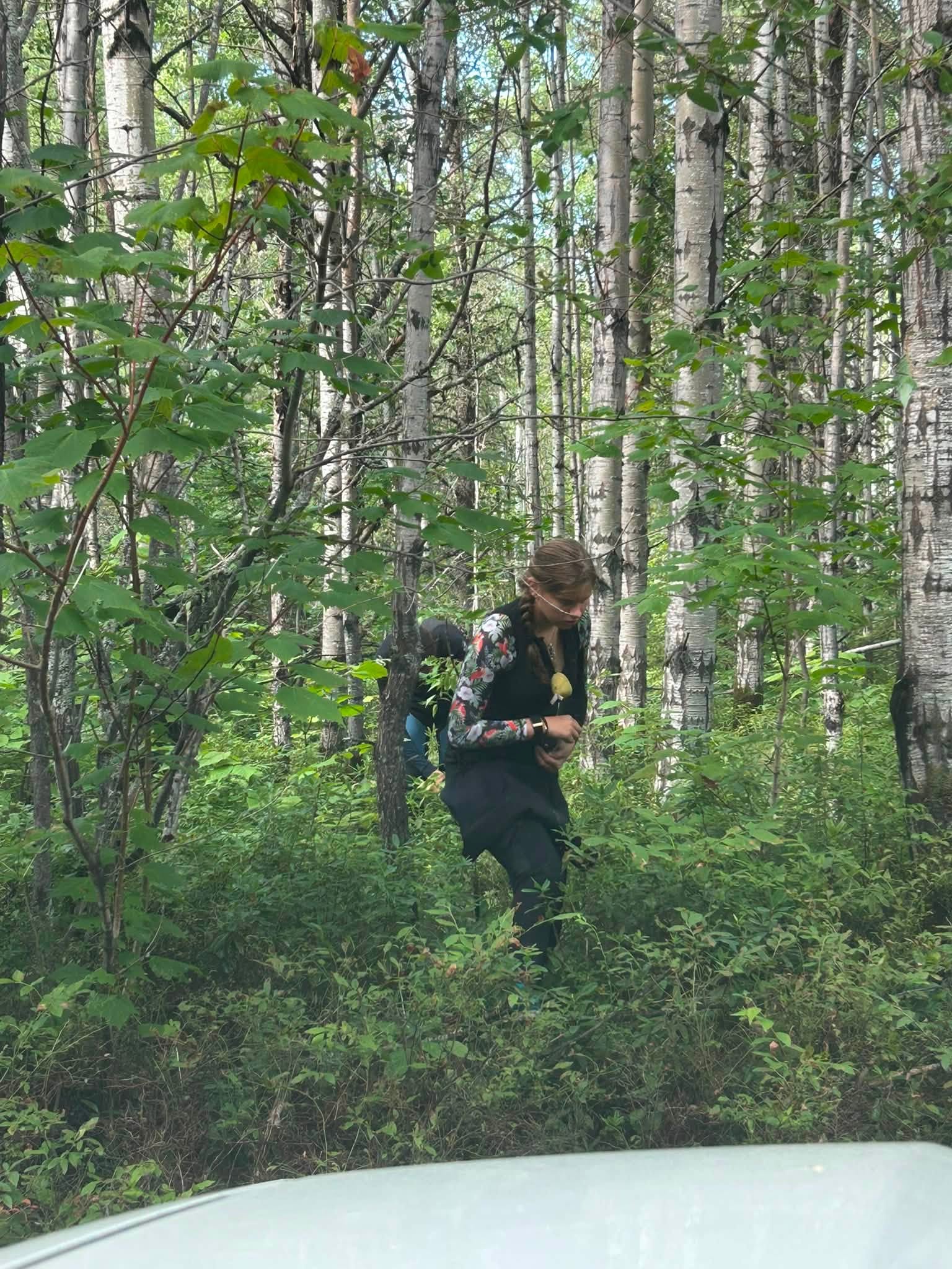 une femme en veste noire se tient dans les bois