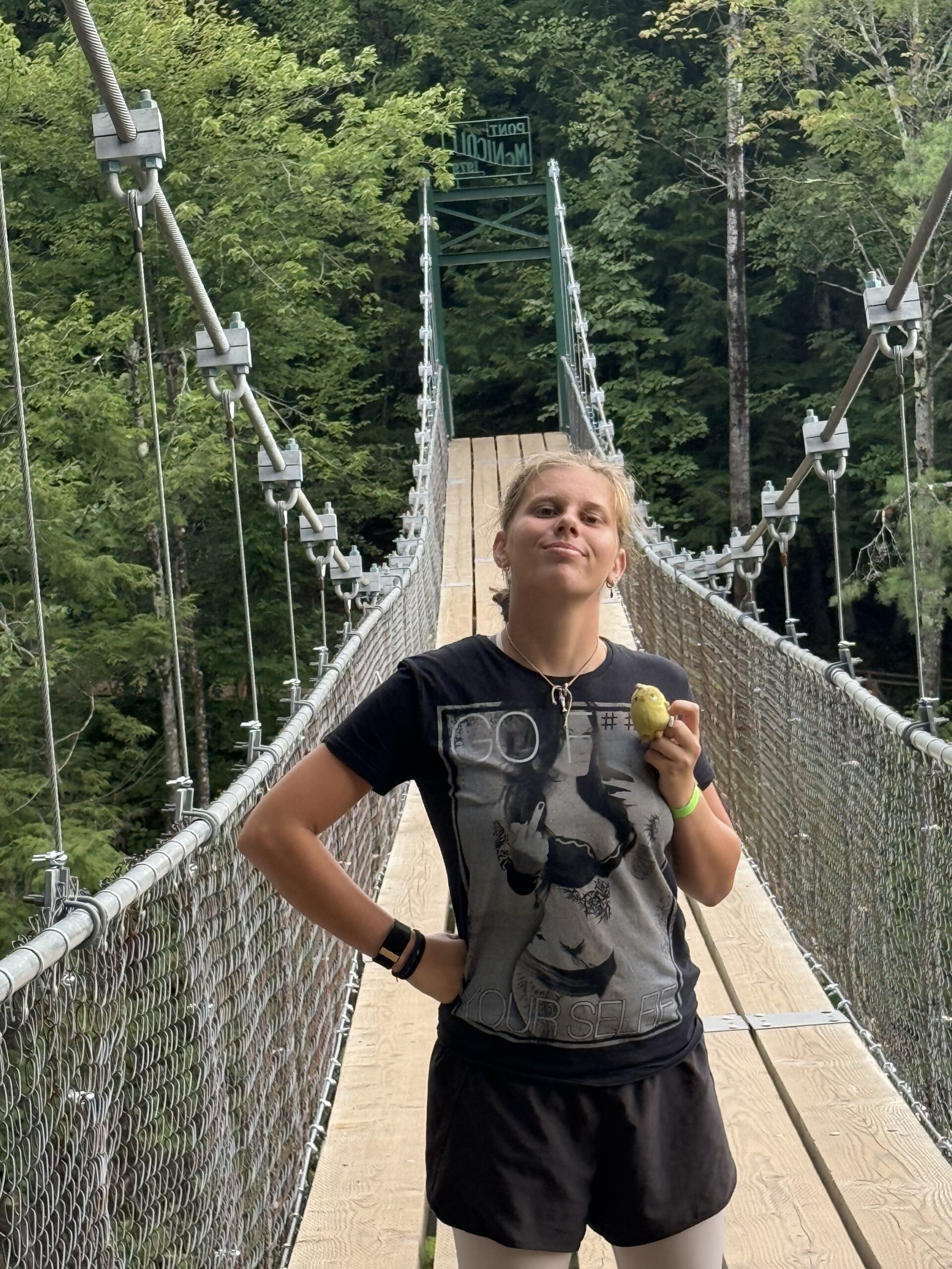 une femme debout sur un pont tenant une balle de tennis, Saint-Ferréol-les-Neiges, Québec, Canada