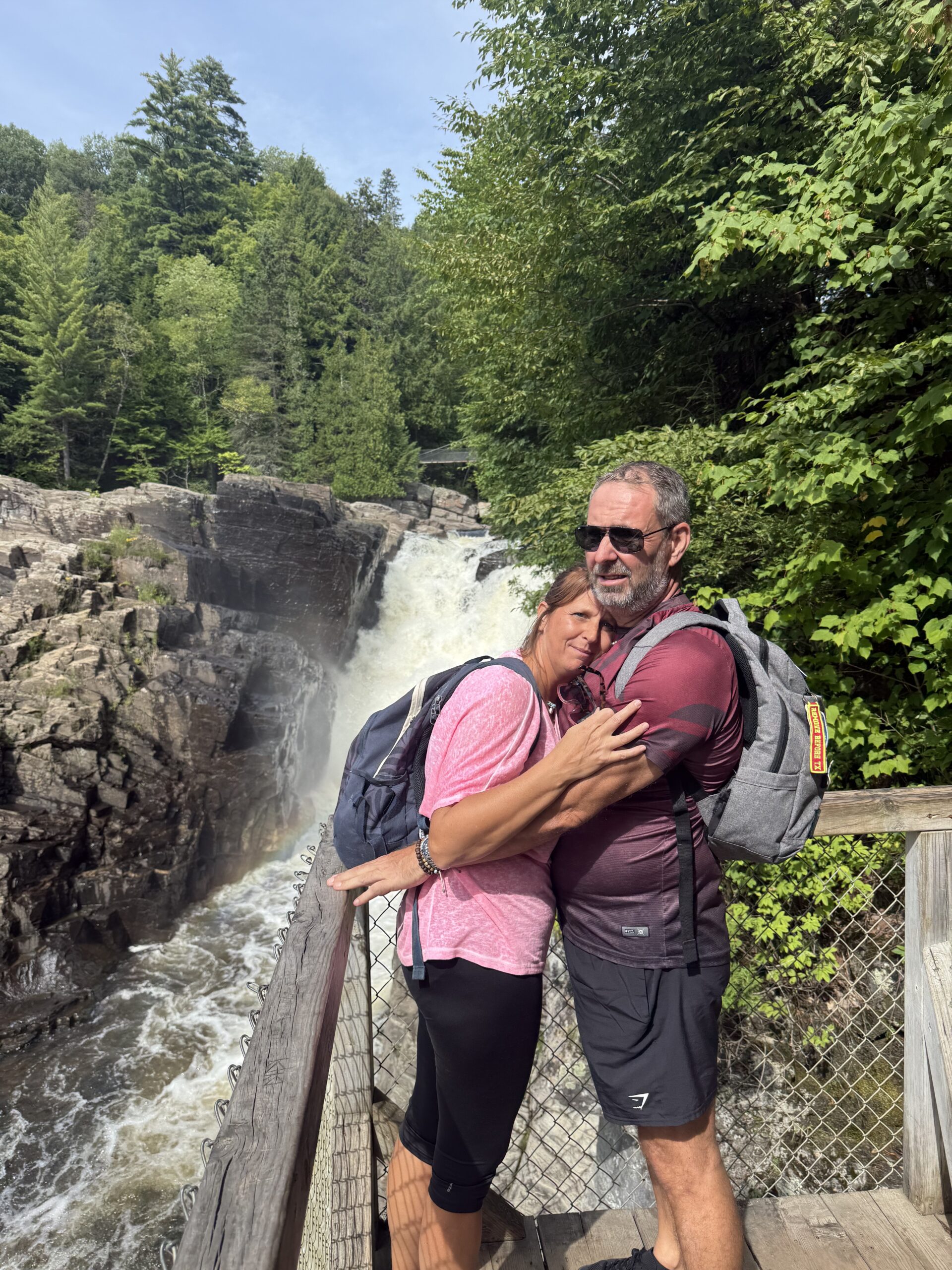 un homme et une femme enlacés sur un pont au-dessus d'une cascade, Saint-Joachim, Québec, Canada