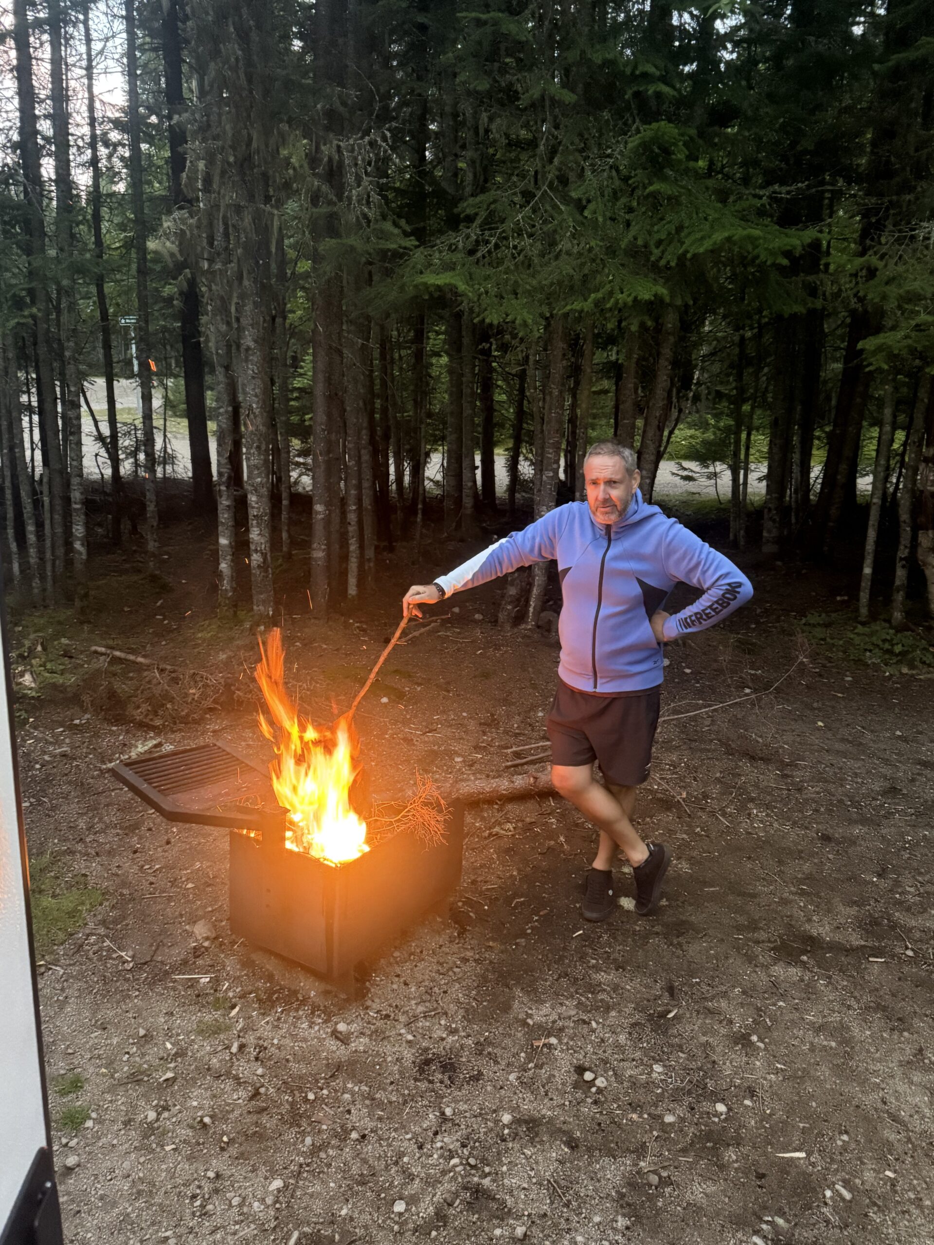 un homme debout près d'un feu en forêt, Lac-Jacques-Cartier, Québec, Canada