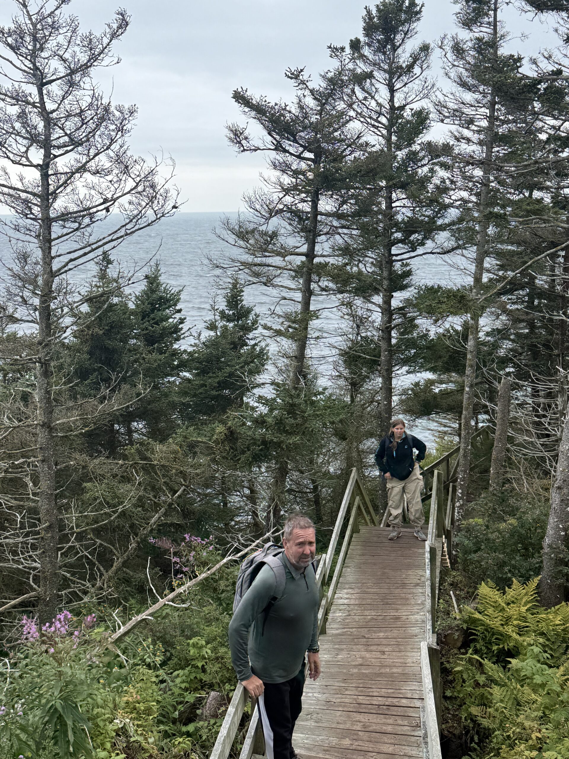 a man walking on a wooden walkway over a lake, Percé, Québec, Canada