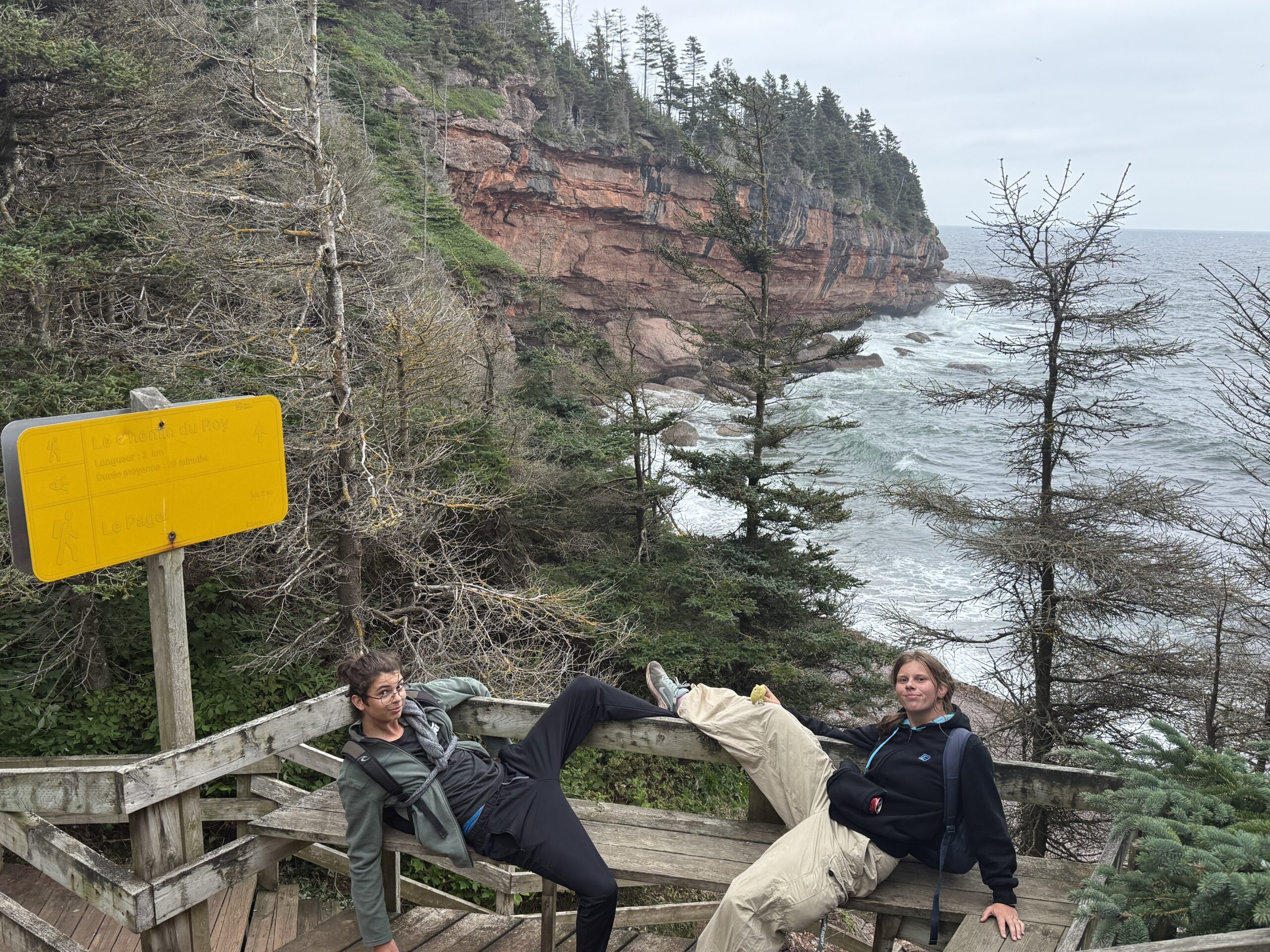 two people sitting on a wooden bench near the ocean, Percé, Québec, Canada