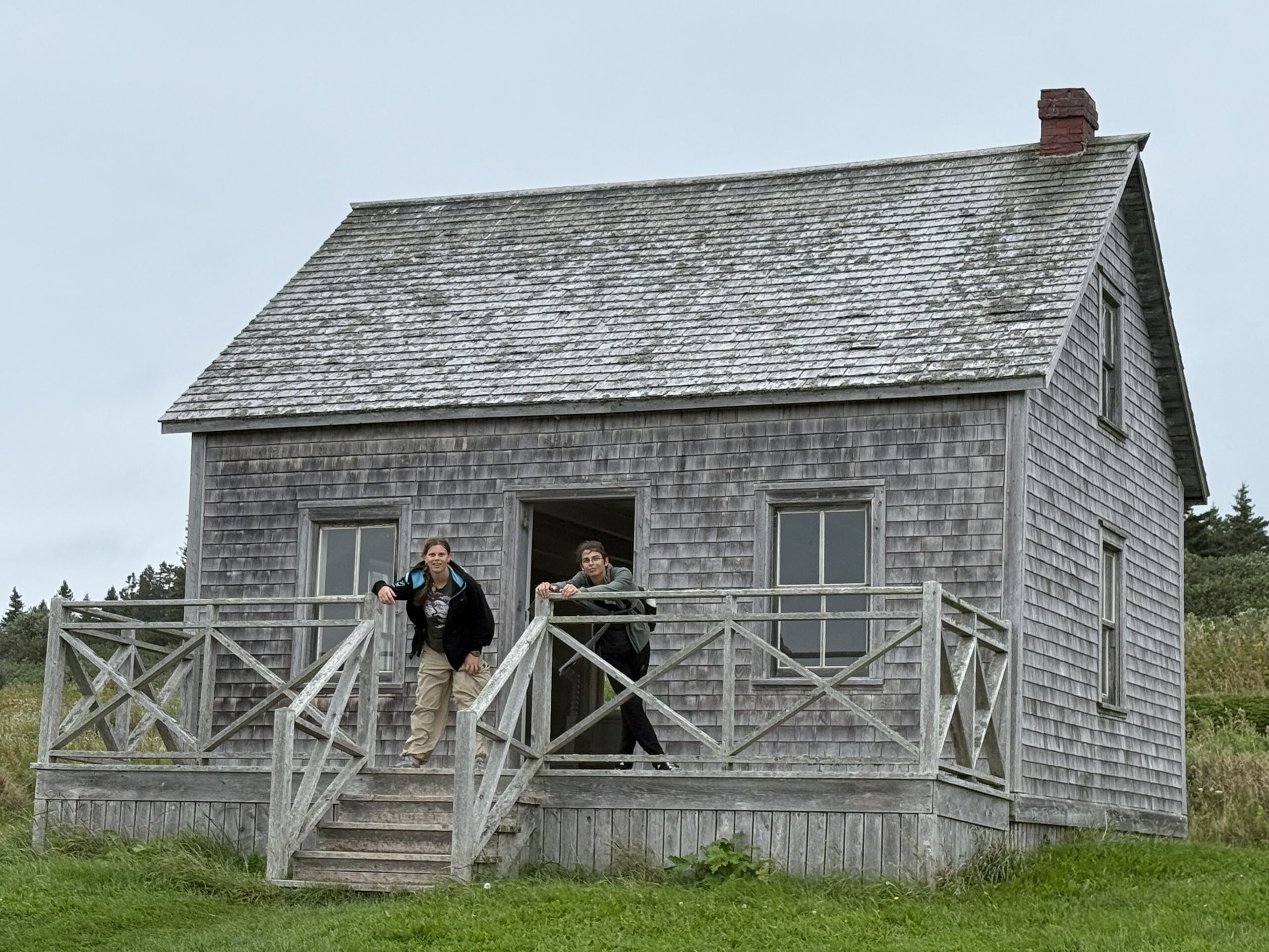 a man standing on a porch next to a house, Percé, Québec, Canada