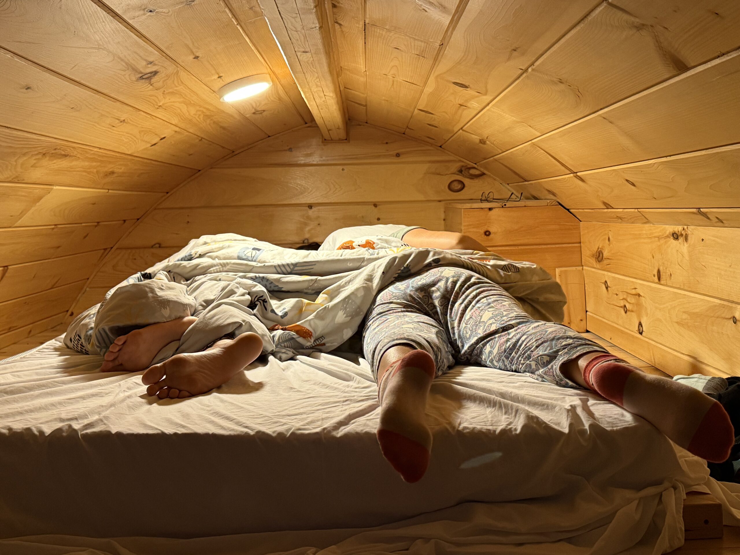 a person laying on a bed in a wooden room, Notre-Dame-de-Bonsecours, Québec, Canada