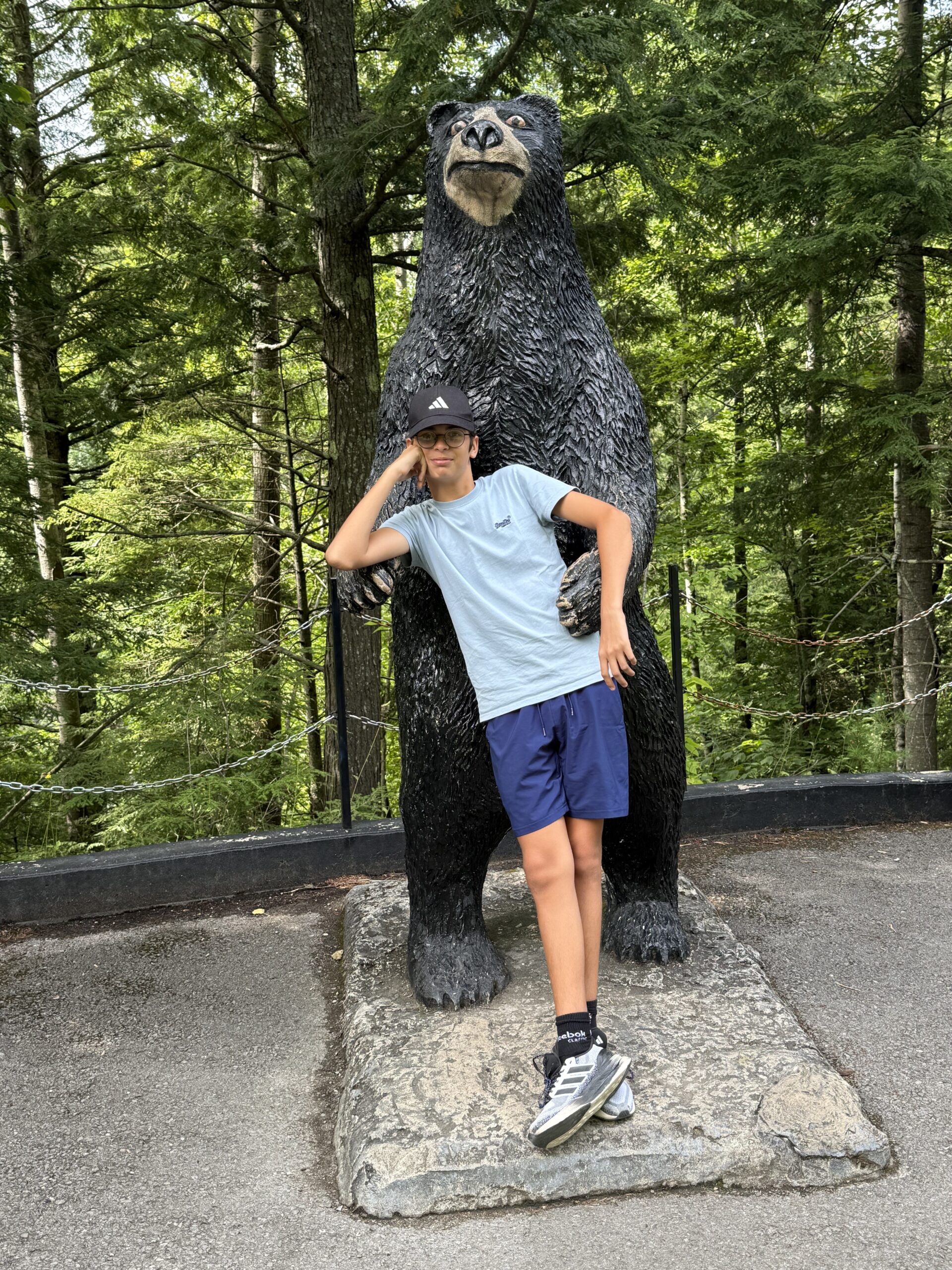 un jeune garçon debout à côté d'une grande statue d'ours, Saint-Joachim, Québec, Canada