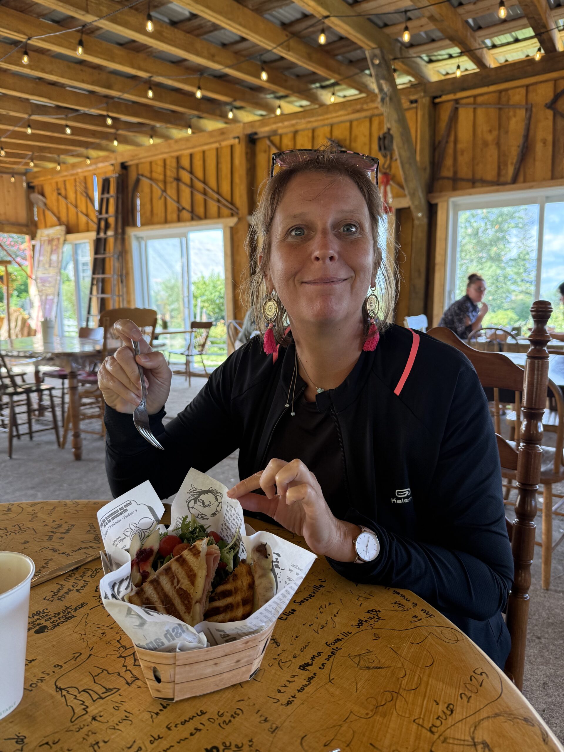 une femme assise à une table en train de manger un sandwich, Métabetchouan–Lac-à-la-Croix, Québec, Canada