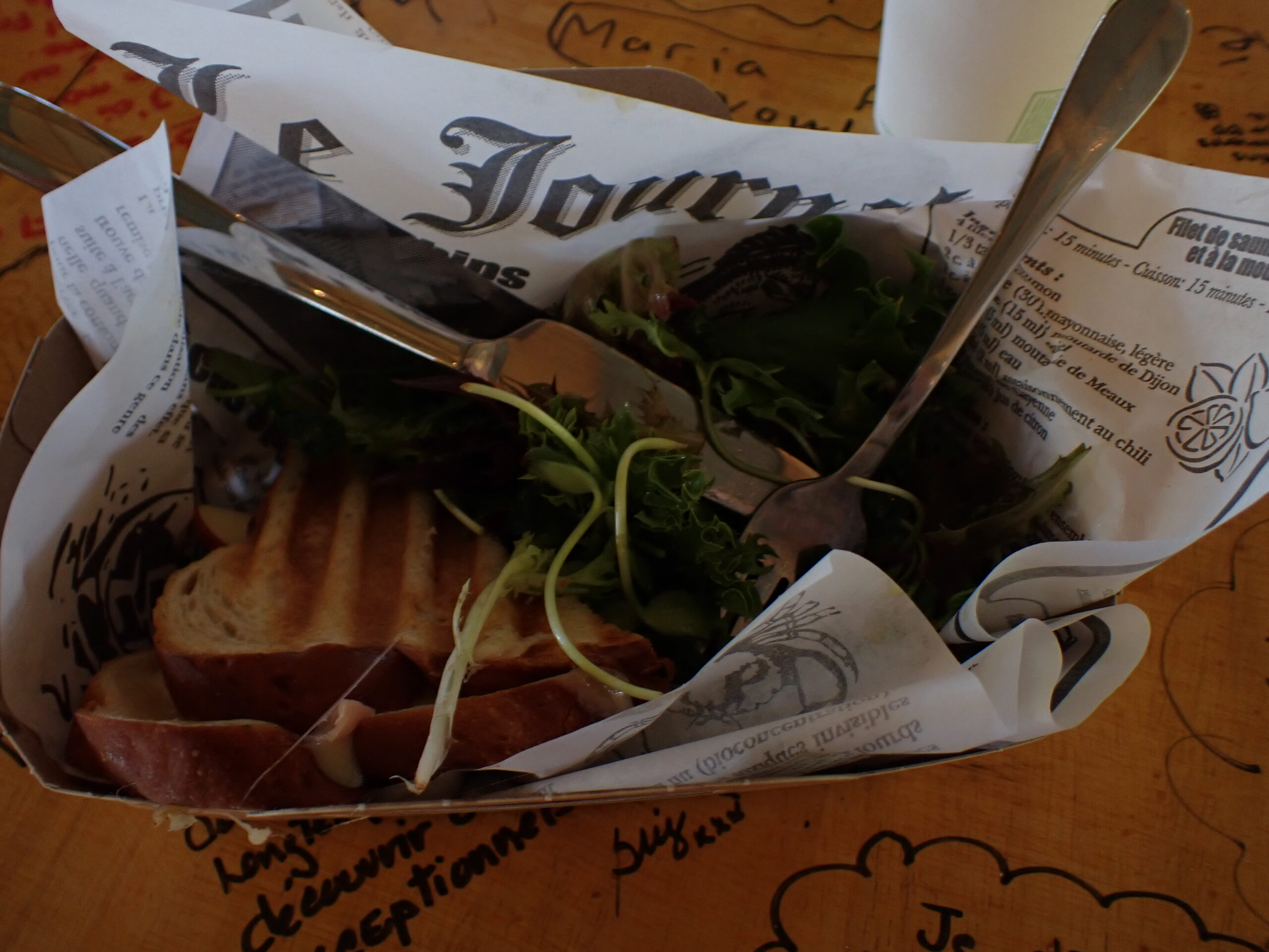 un sandwich avec de la viande et des légumes verts dans un contenant en papier