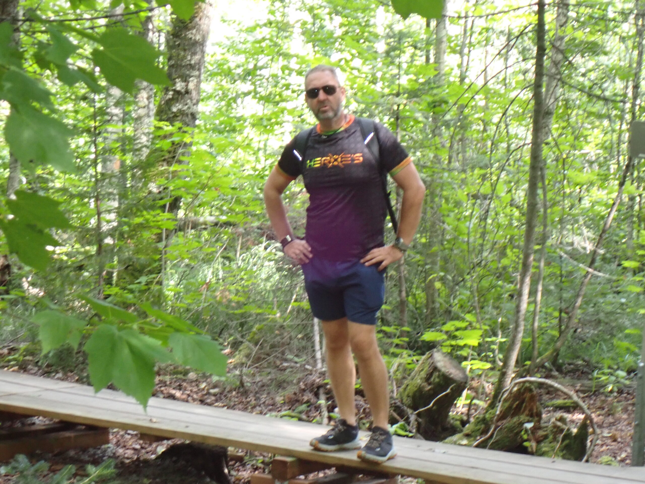 Un homme en chemise violette et short est sur un pont en bois