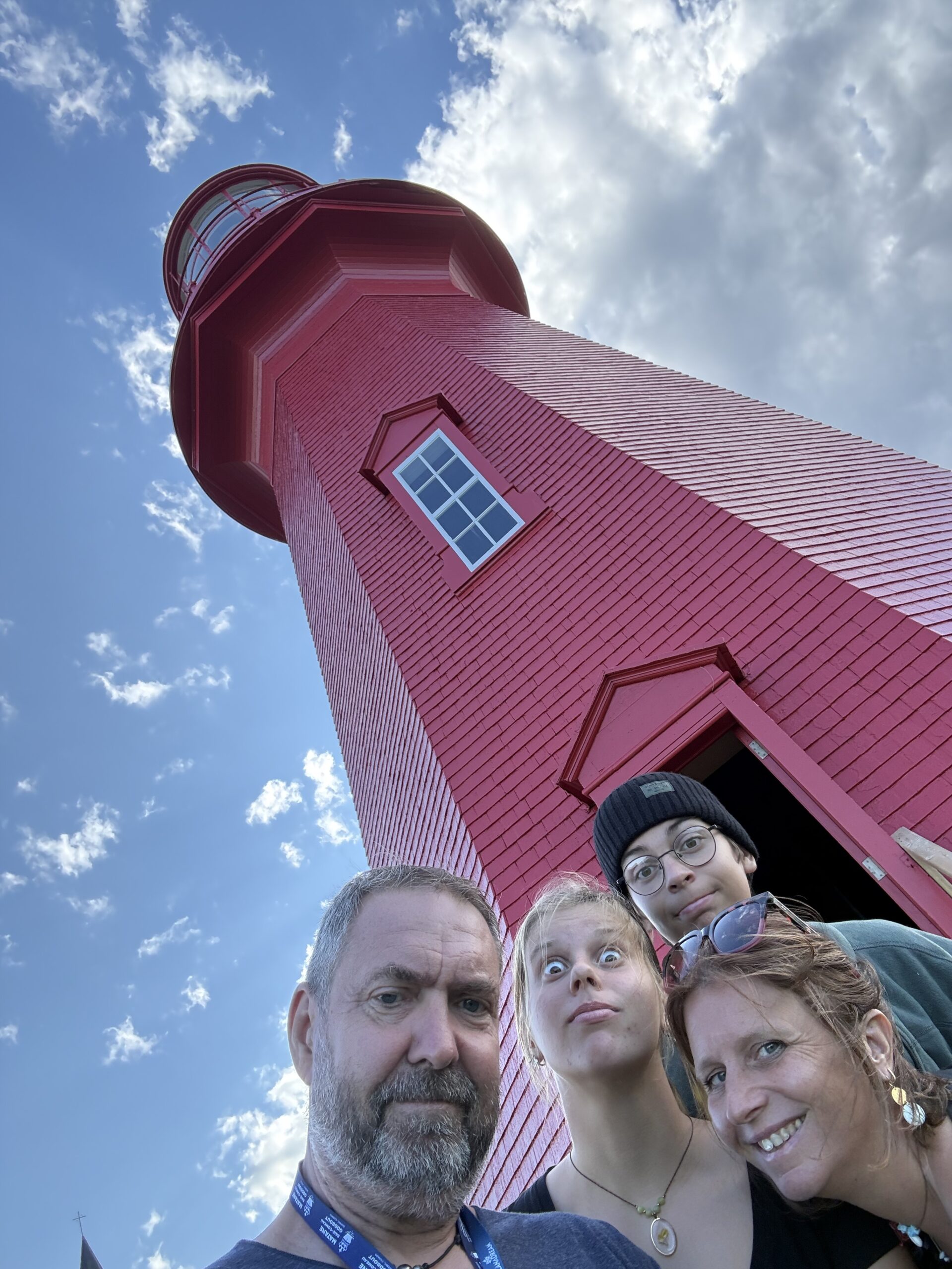 un groupe de personnes debout devant un phare rouge, La Martre, Québec, Canada
