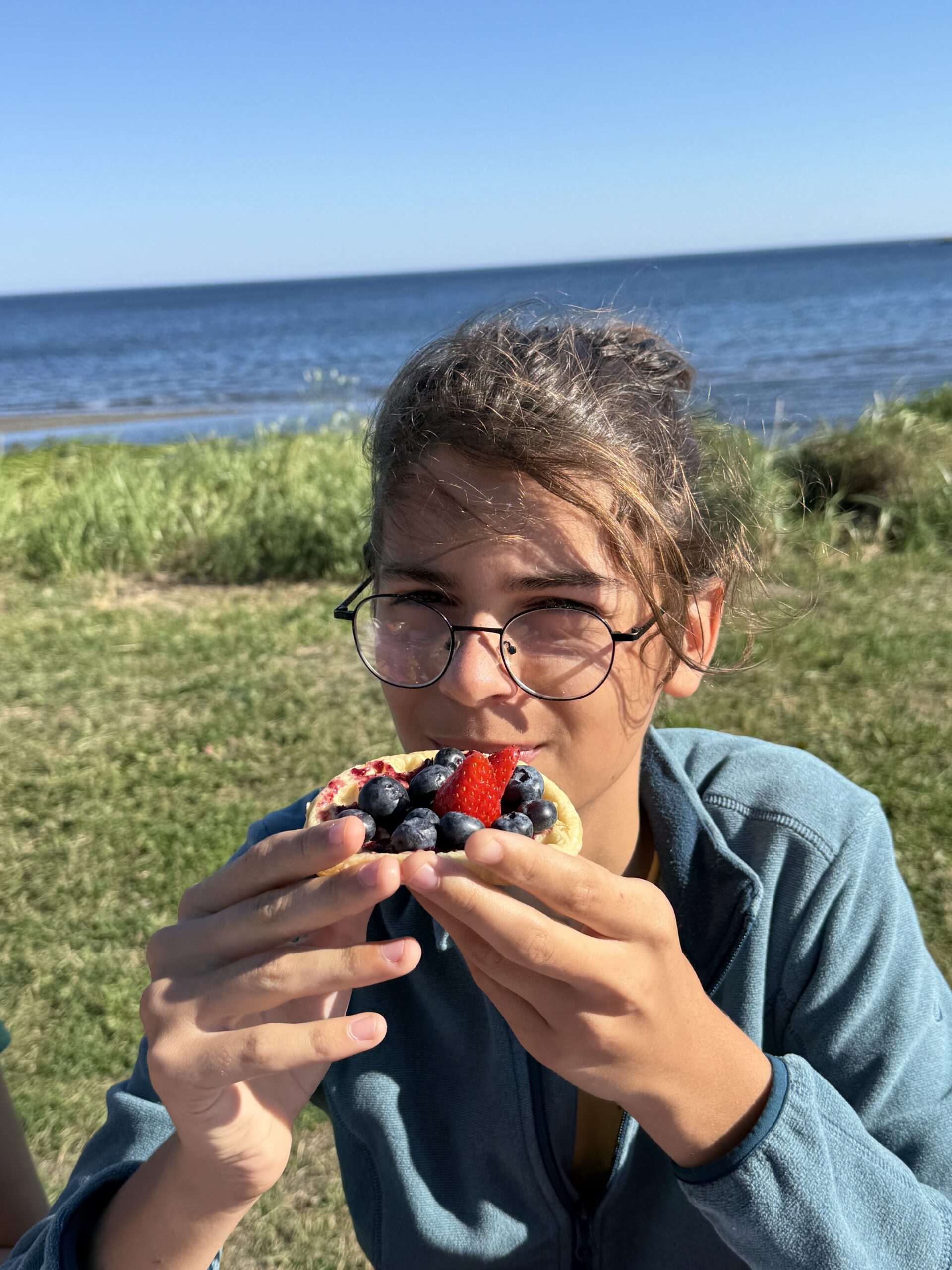 a girl eating a piece of fruit on a beach, Saint-Maxime-du-Mont-Louis, Québec, Canada