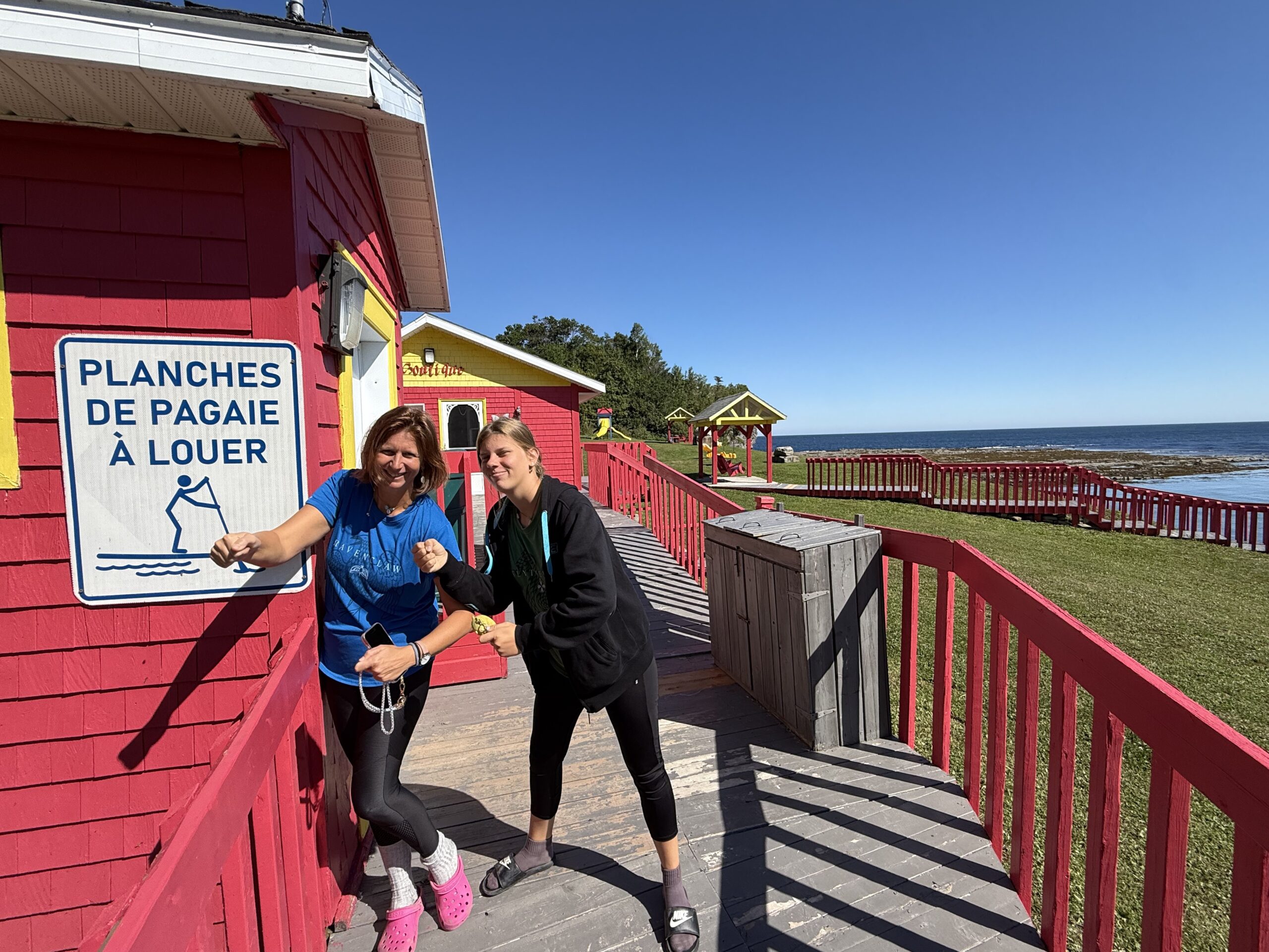 a woman and a man standing on a boardwalk, Cloridorme, Québec, Canada