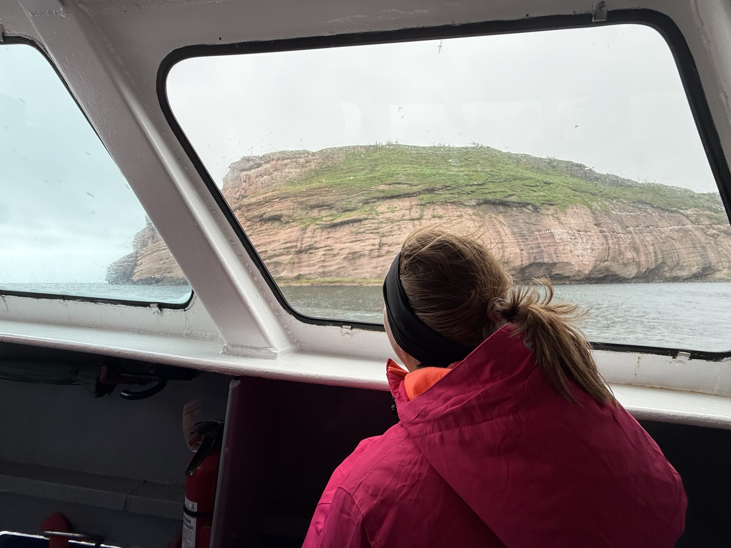 a woman in a pink jacket looking out the window of a boat, Québec, Canada