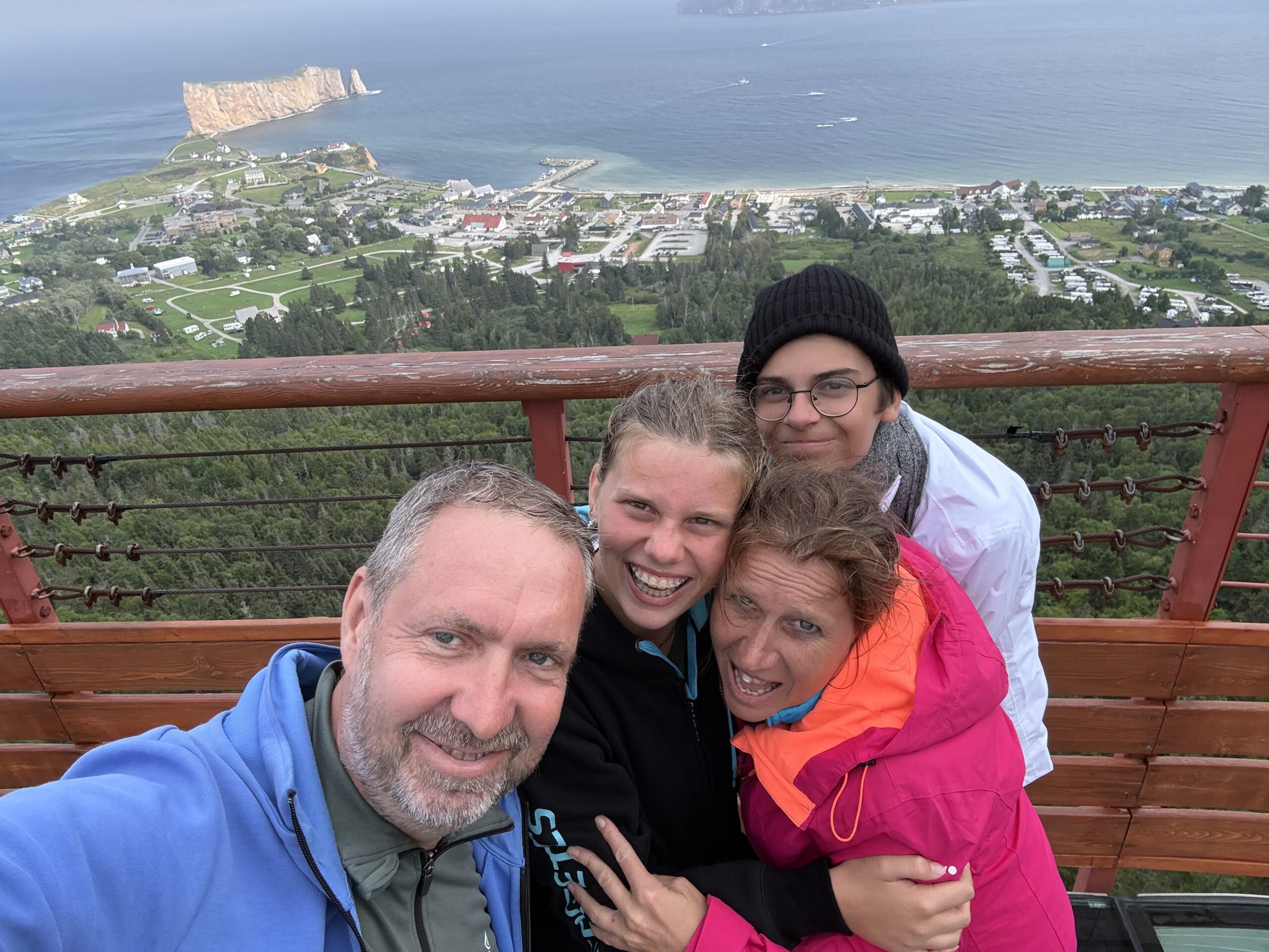 a family poses for a picture on a bench overlooking the ocean, Percé, Québec, Canada