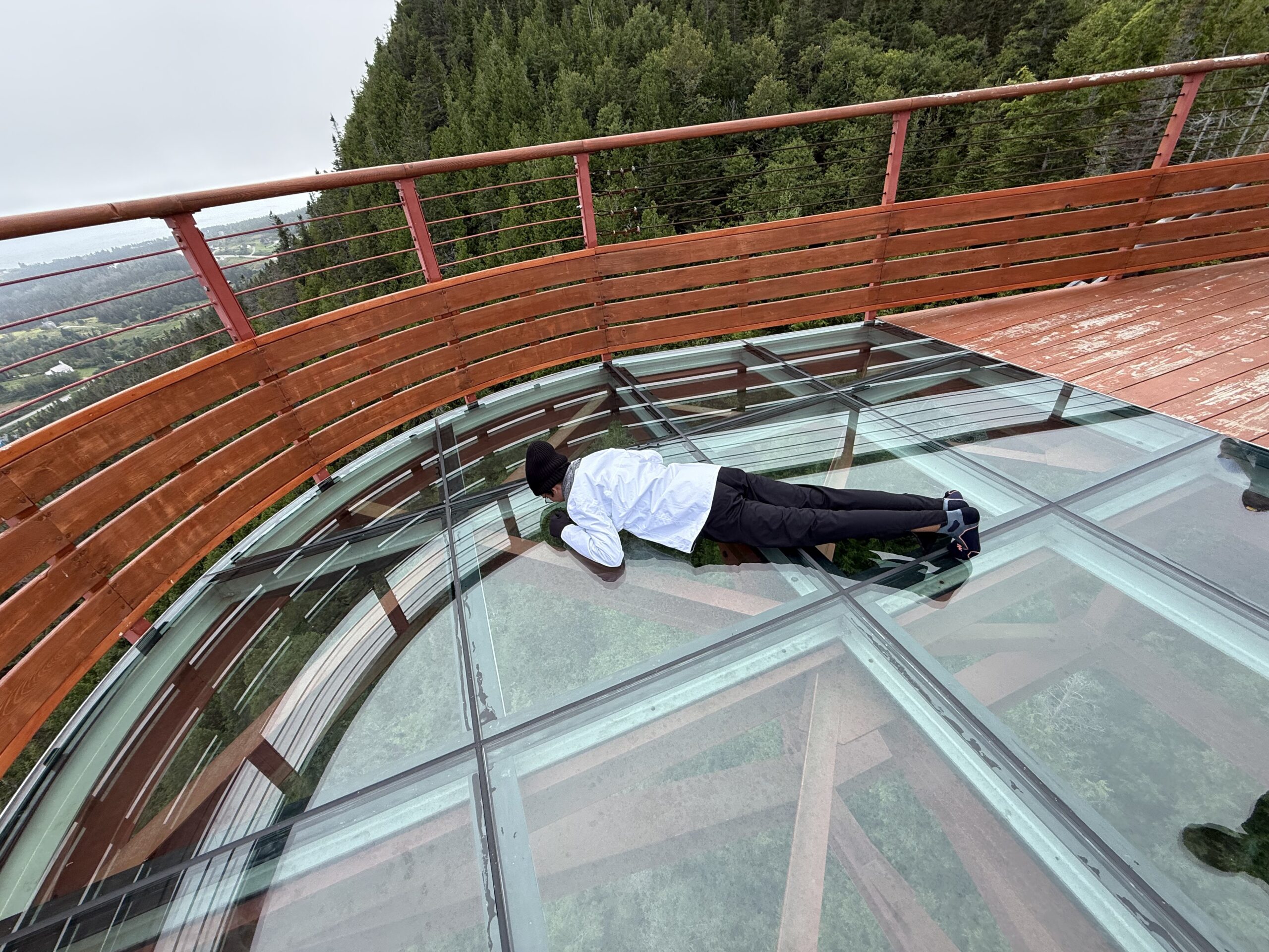 a man laying on a glass floor, Percé, Québec, Canada