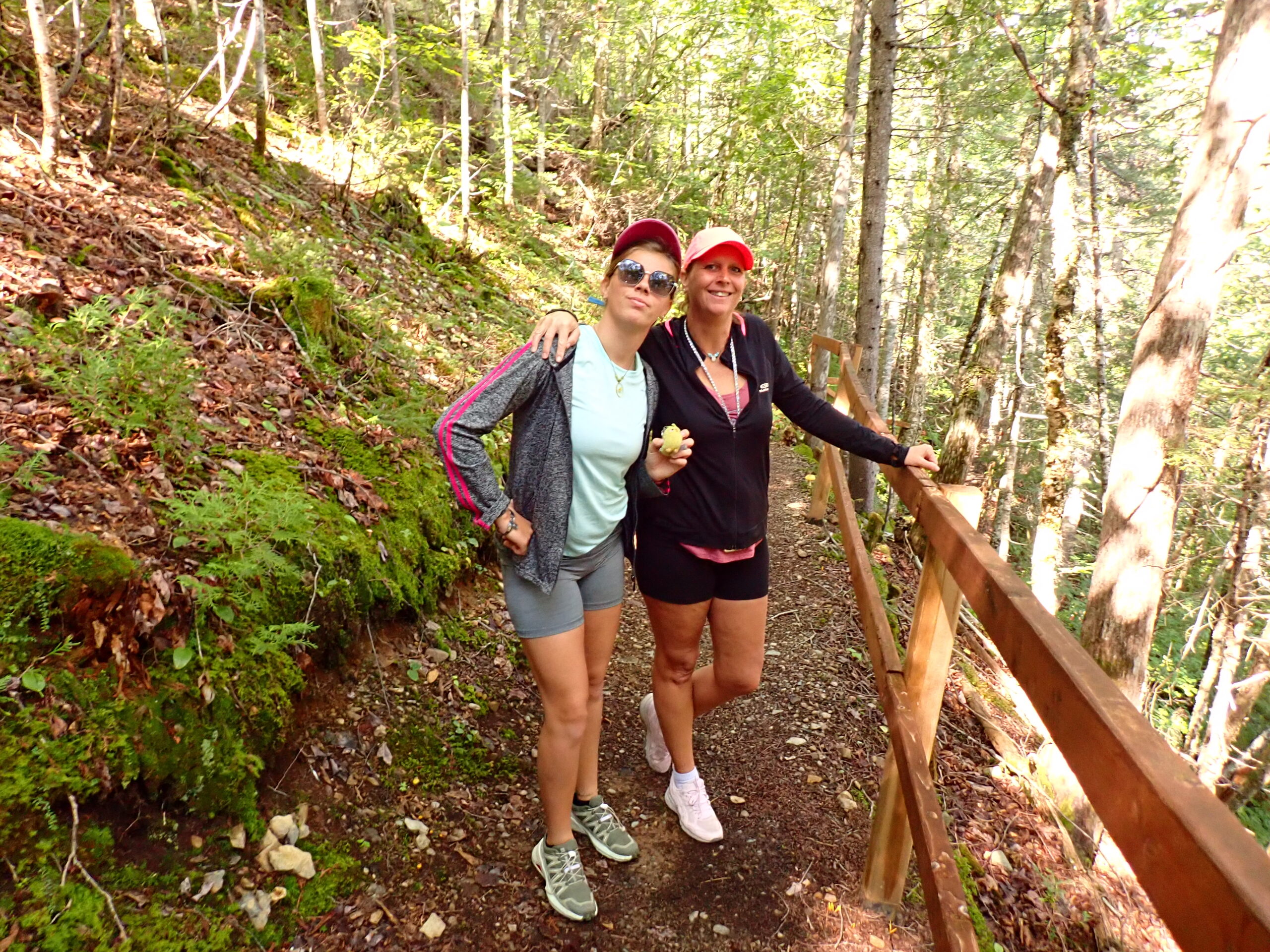 two women walking up a trail in the woods