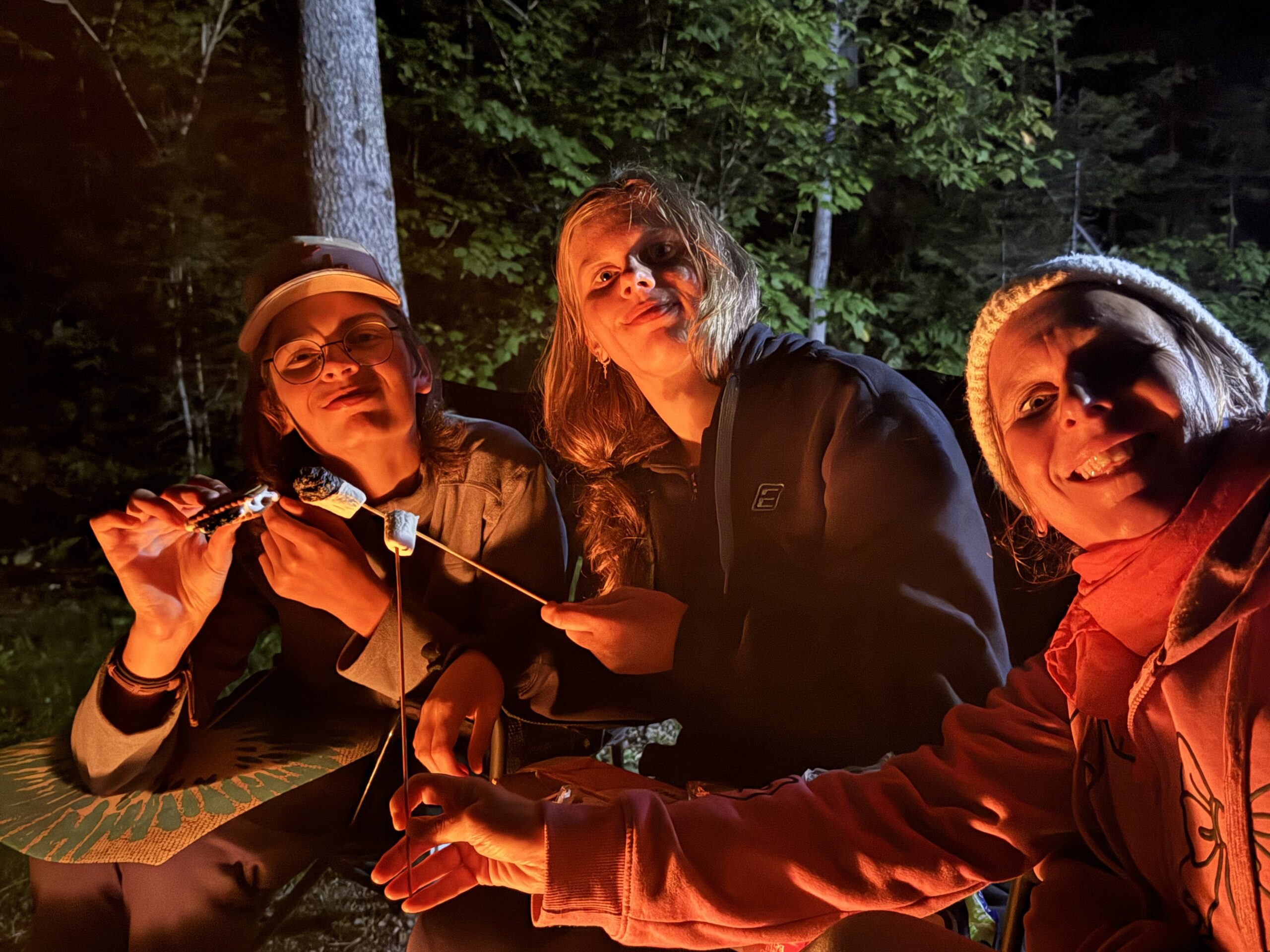 three people sitting around a fire, Port-Daniel, Québec, Canada