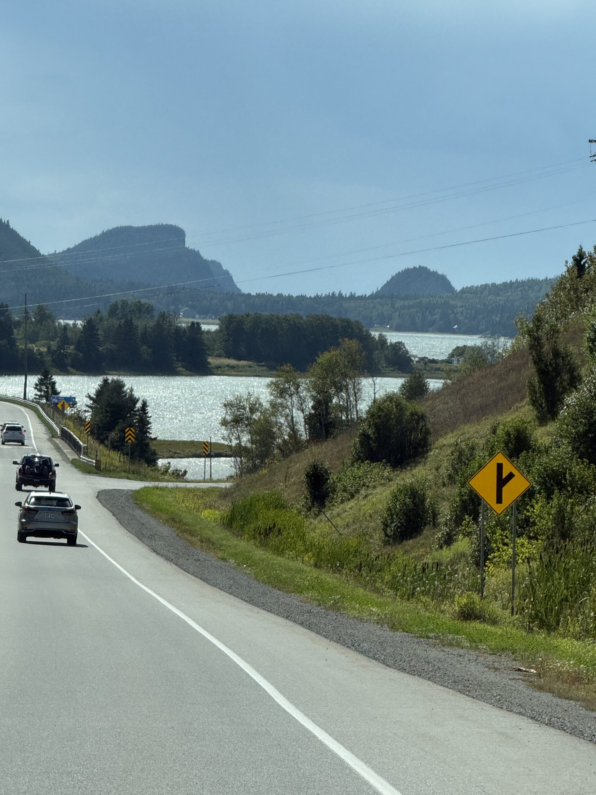 a car driving down a road next to a lake