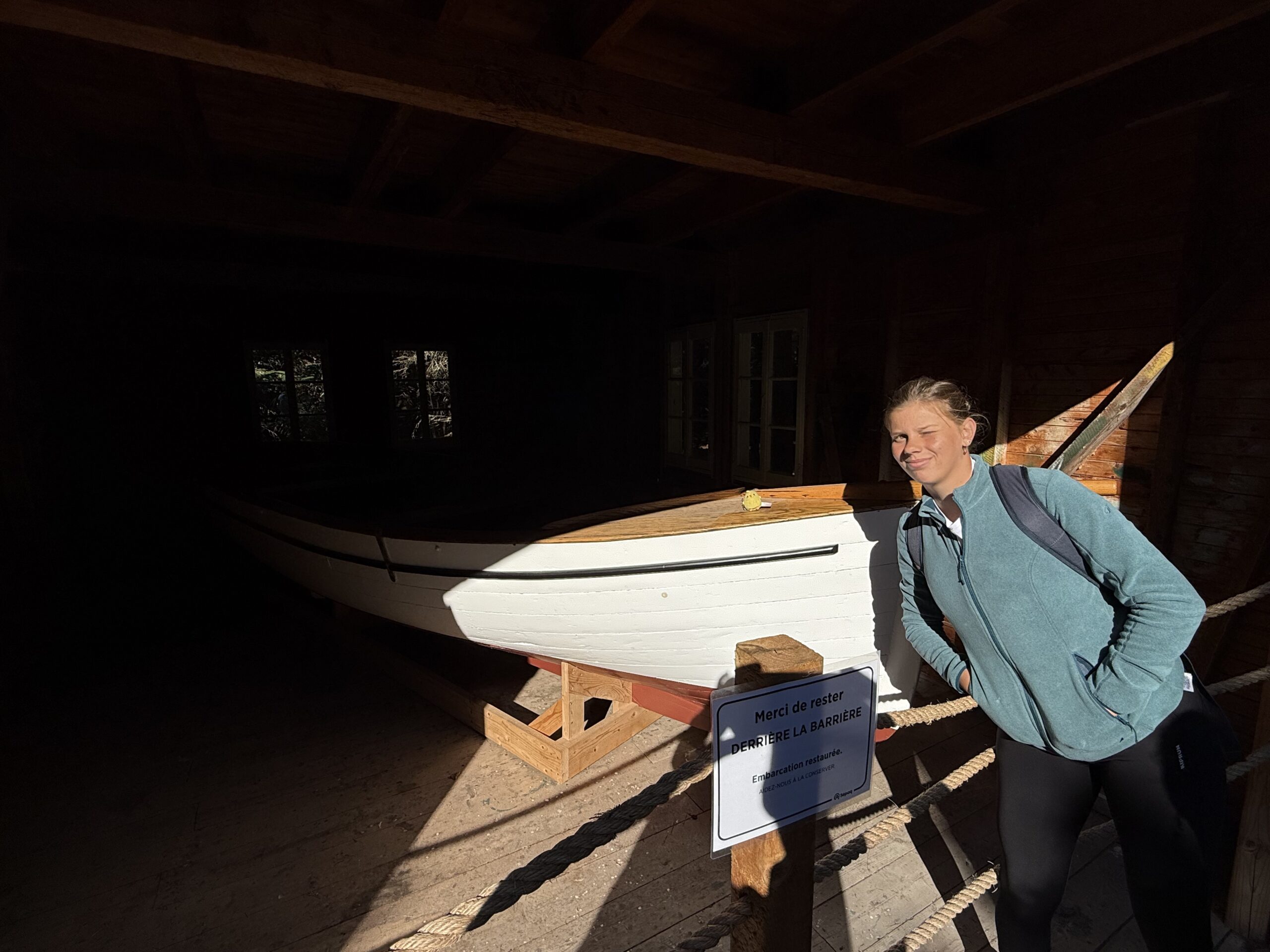 a woman standing next to a boat in a shed, Rimouski, Québec, Canada