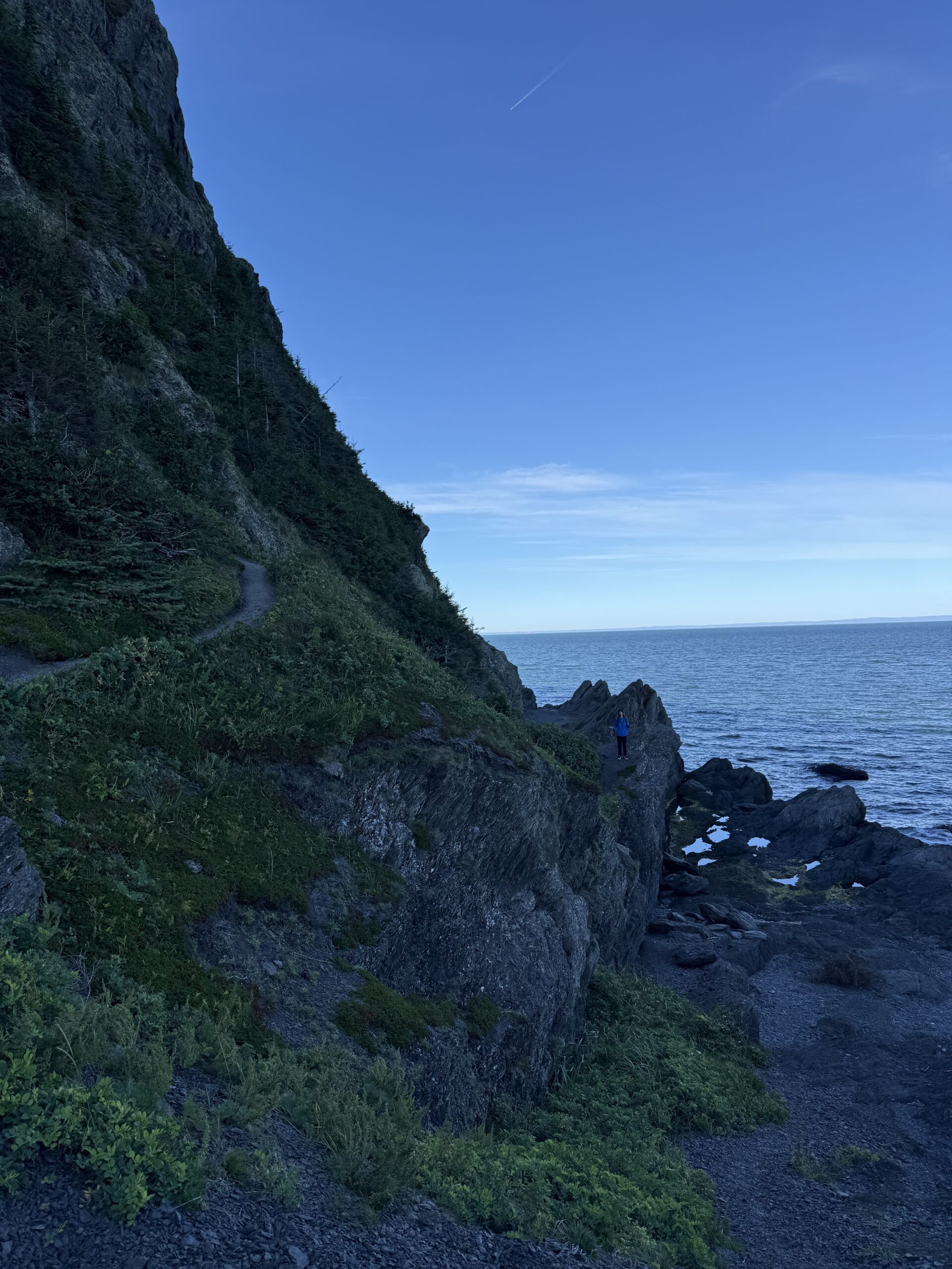 a person is standing on a rocky cliff, Rimouski, Québec, Canada
