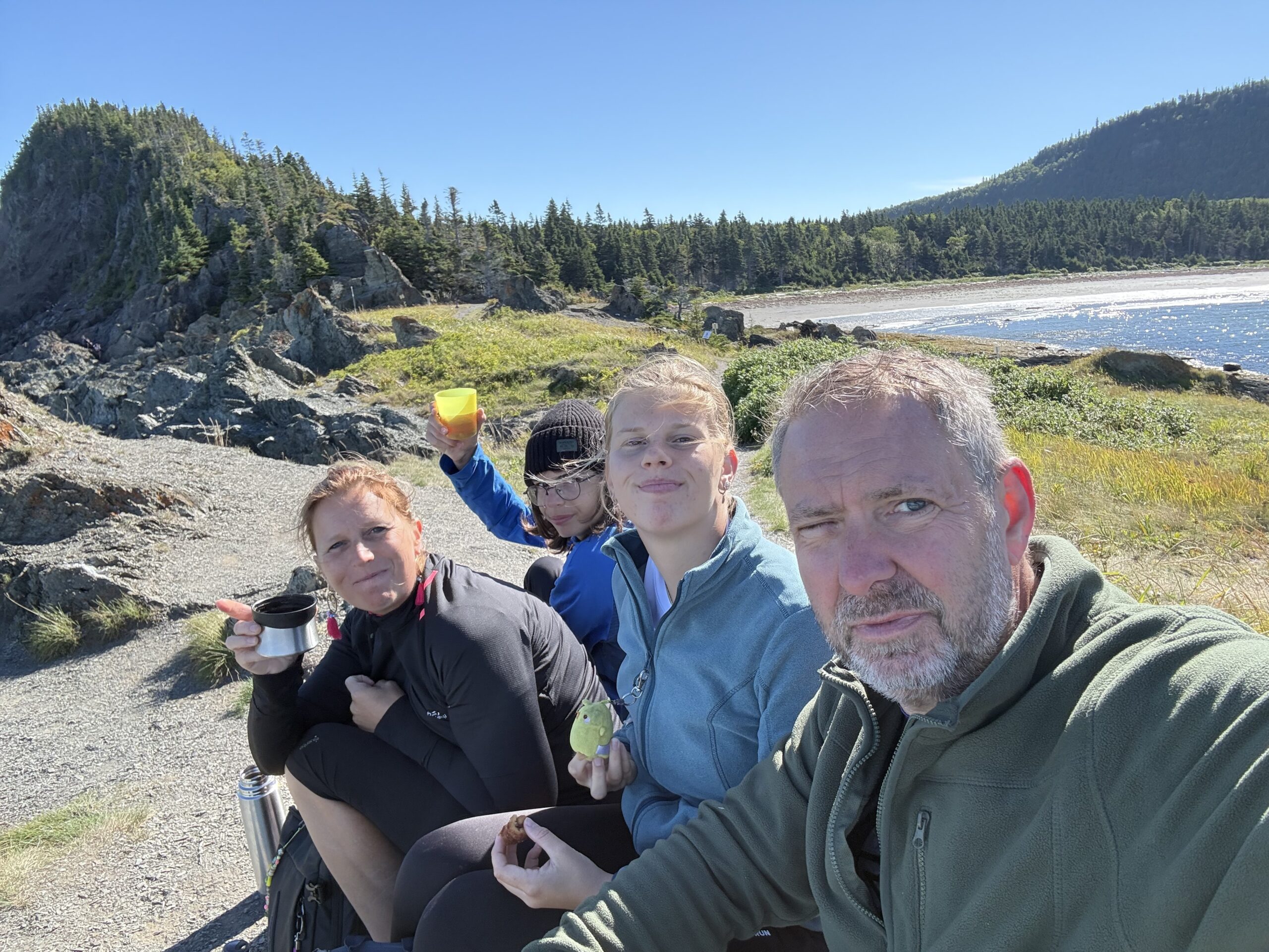 a group of people sitting on a rocky beach, Rimouski, Québec, Canada