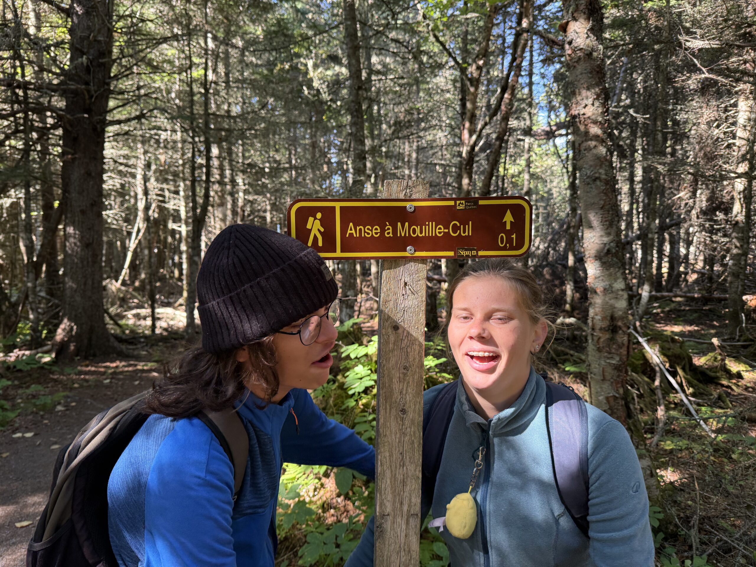 two girls standing next to a sign in the woods, Rimouski, Québec, Canada