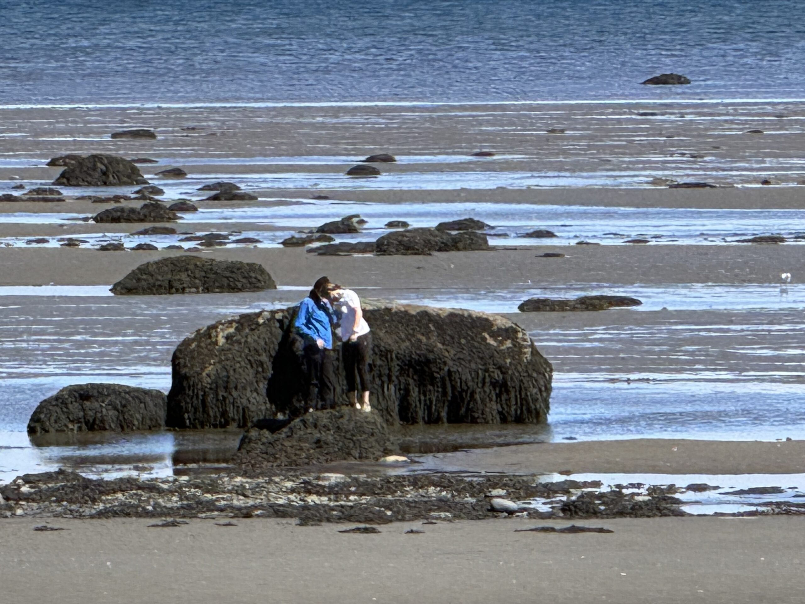 a person sitting on a rock on the beach, Rimouski, Québec, Canada